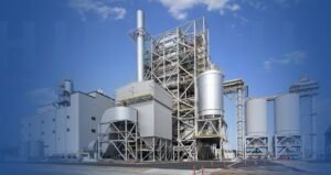 A large industrial plant set against a clear blue sky, showcasing its towering structures and expansive layout.