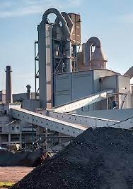 A large coal plant featuring a conveyor belt and a substantial pile of coal in the foreground.